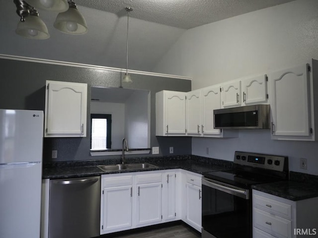 kitchen with appliances with stainless steel finishes, dark hardwood / wood-style flooring, sink, white cabinets, and lofted ceiling