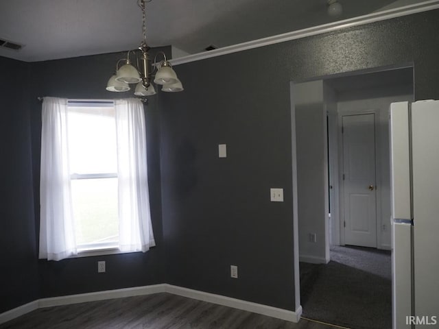 empty room featuring a notable chandelier and dark hardwood / wood-style floors