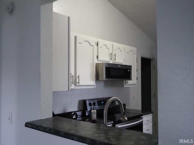 kitchen featuring white cabinets, stainless steel appliances, and lofted ceiling