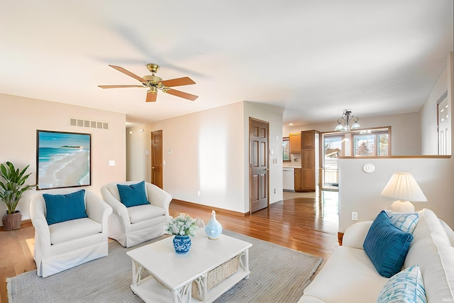 living room featuring wood-type flooring and ceiling fan with notable chandelier