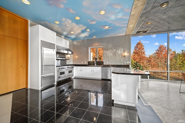 kitchen featuring a kitchen breakfast bar, exhaust hood, sink, high quality appliances, and white cabinetry