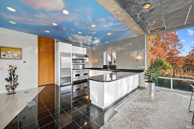 kitchen with white cabinetry, sink, exhaust hood, high end appliances, and kitchen peninsula