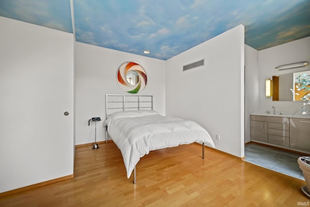 bedroom with sink, wood-type flooring, and vaulted ceiling