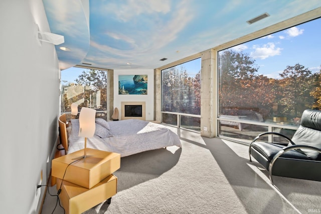 bedroom featuring multiple windows, carpet floors, and a wall of windows