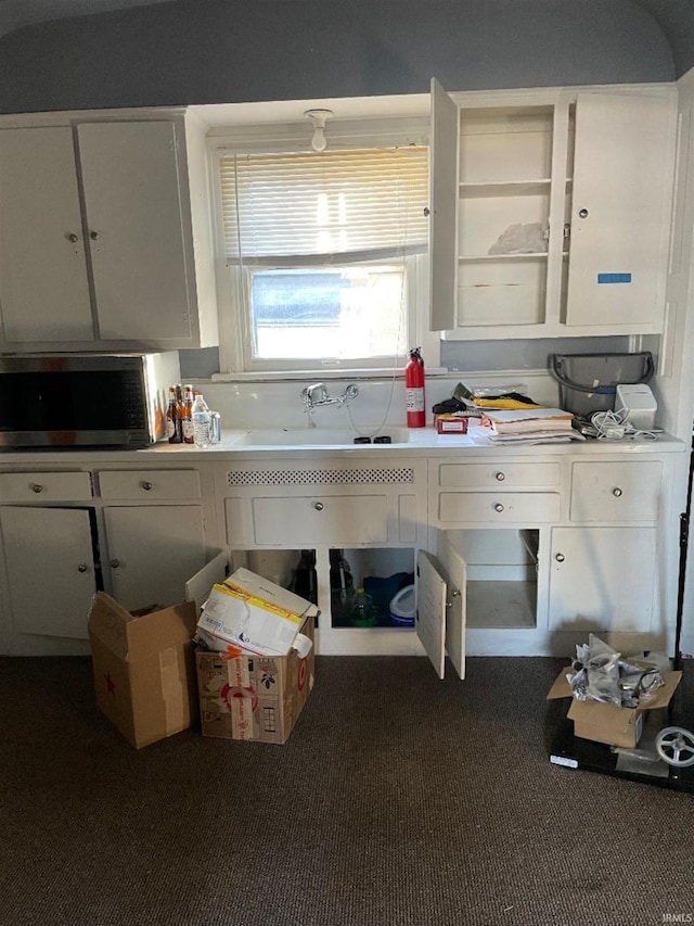 kitchen featuring white cabinets, sink, and dark colored carpet