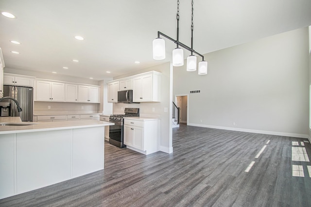 kitchen featuring white cabinetry, sink, hanging light fixtures, dark wood-type flooring, and appliances with stainless steel finishes