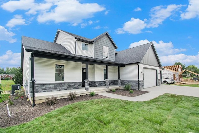 view of front of house with covered porch, a garage, a front lawn, and central air condition unit