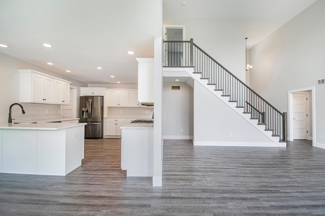 kitchen with white cabinetry, stainless steel refrigerator with ice dispenser, sink, dark wood-type flooring, and kitchen peninsula