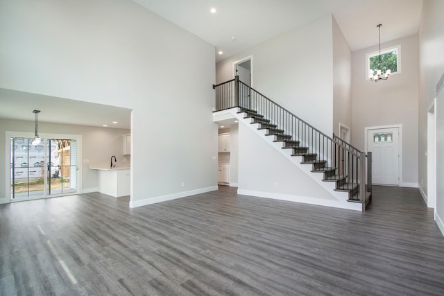 interior space featuring a towering ceiling, an inviting chandelier, dark wood-type flooring, and plenty of natural light