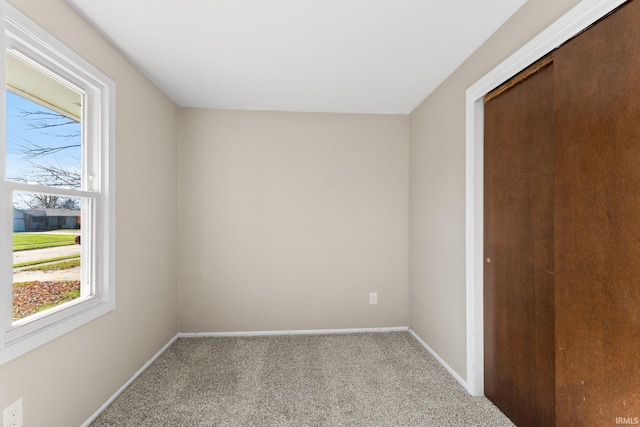 unfurnished bedroom featuring multiple windows, light carpet, and a closet