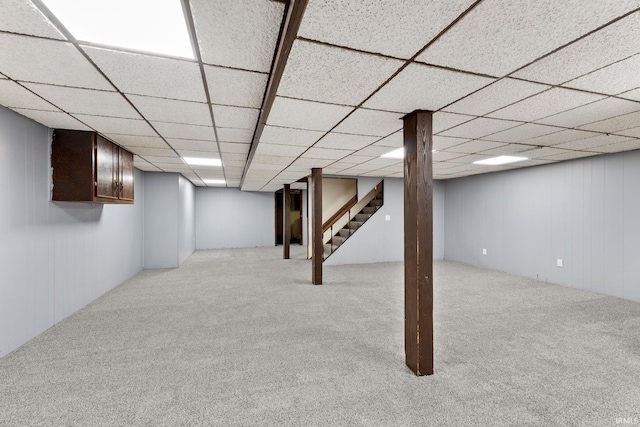 basement featuring light carpet and a drop ceiling