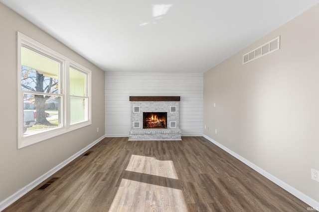 unfurnished living room featuring wooden walls and dark wood-type flooring