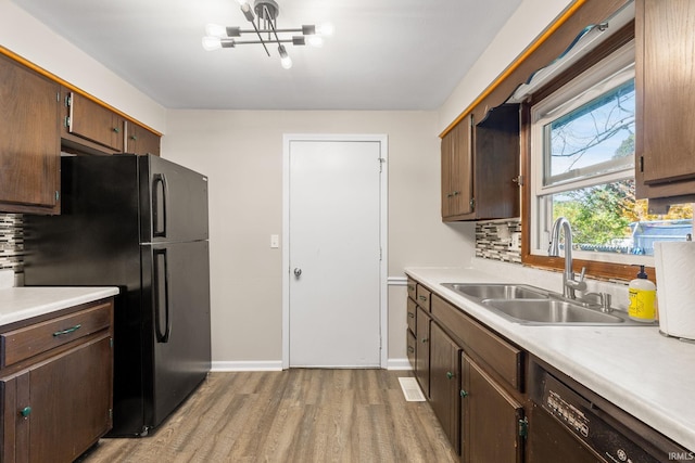 kitchen featuring sink, black appliances, light hardwood / wood-style floors, backsplash, and dark brown cabinetry