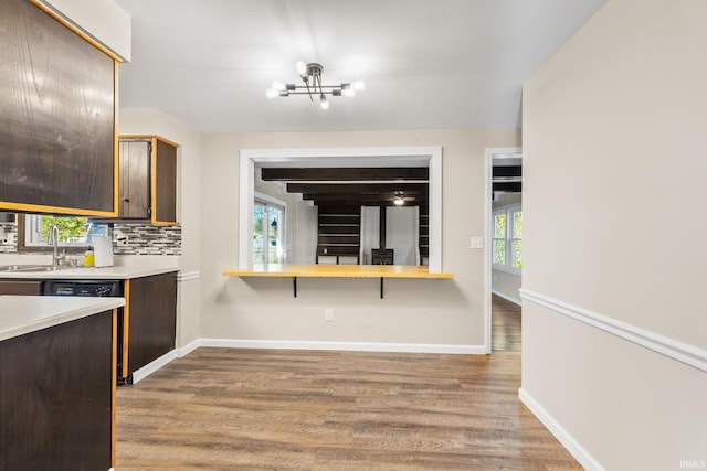 kitchen featuring sink, light hardwood / wood-style floors, a chandelier, backsplash, and dark brown cabinetry