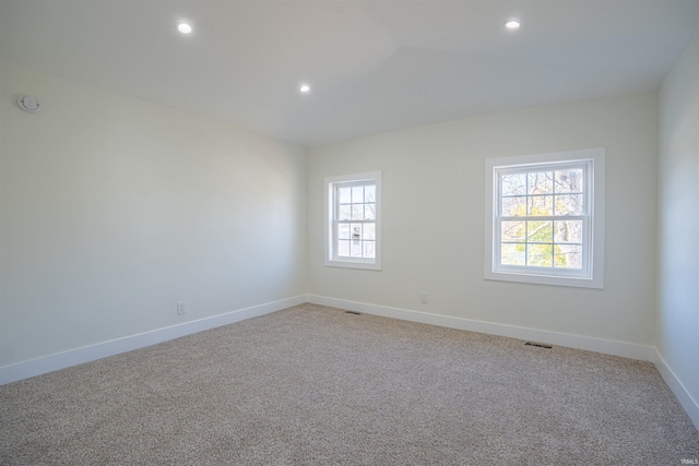 carpeted empty room featuring vaulted ceiling