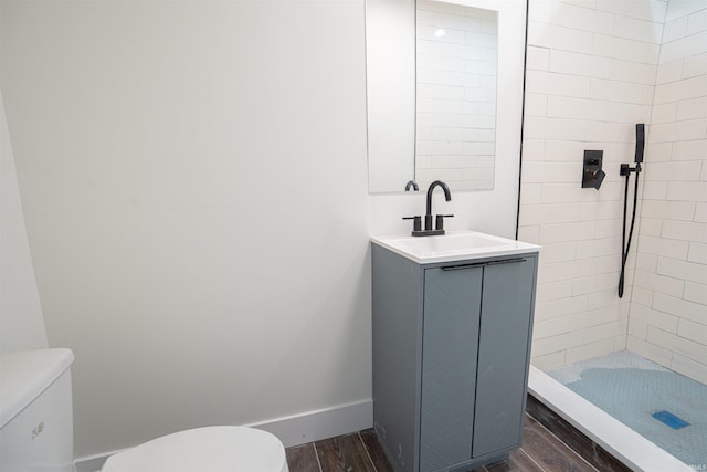 bathroom with vanity, toilet, wood-type flooring, and tiled shower