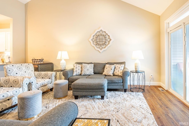 living room featuring vaulted ceiling, a healthy amount of sunlight, and hardwood / wood-style floors