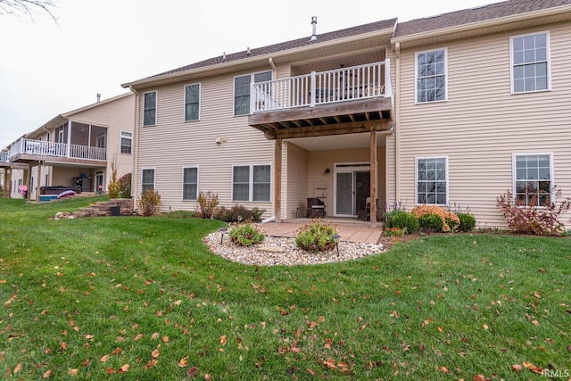 rear view of house featuring a patio area, a yard, and a balcony