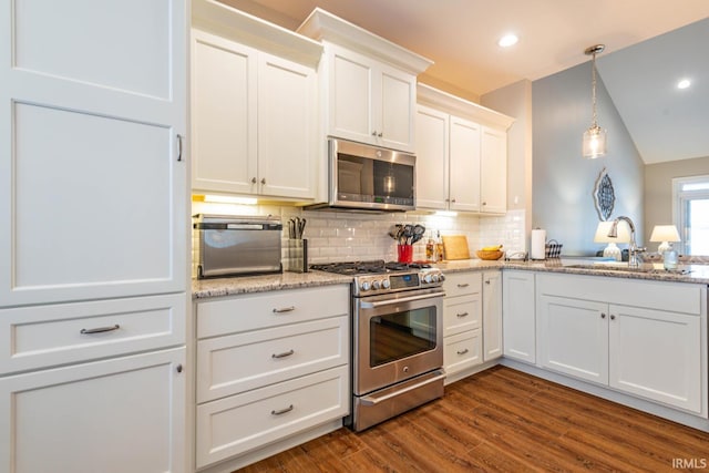 kitchen featuring white cabinetry, sink, dark hardwood / wood-style floors, pendant lighting, and appliances with stainless steel finishes