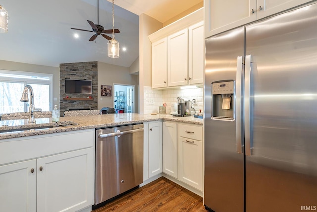 kitchen featuring white cabinetry, sink, a fireplace, appliances with stainless steel finishes, and dark hardwood / wood-style flooring