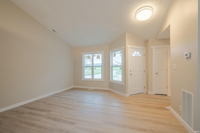 entrance foyer featuring a textured ceiling, light hardwood / wood-style floors, and vaulted ceiling