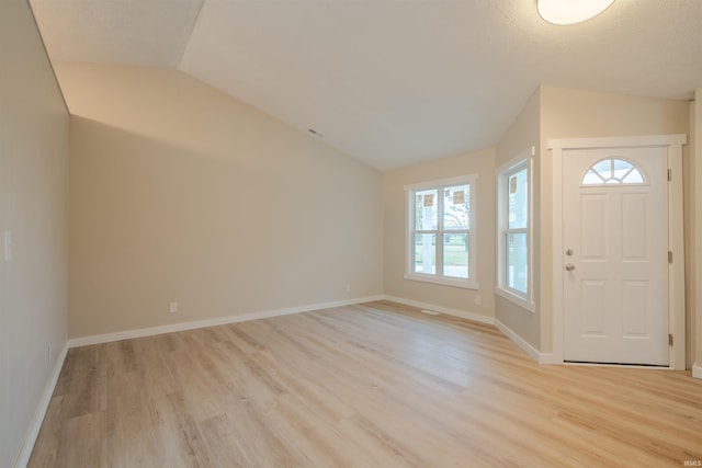 entrance foyer featuring a textured ceiling, vaulted ceiling, and light hardwood / wood-style flooring