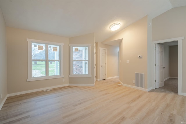 empty room with light hardwood / wood-style flooring and lofted ceiling