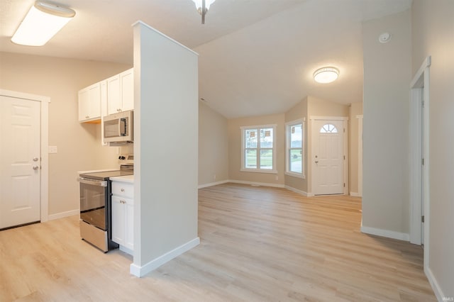 kitchen with light hardwood / wood-style flooring, white cabinets, vaulted ceiling, and appliances with stainless steel finishes