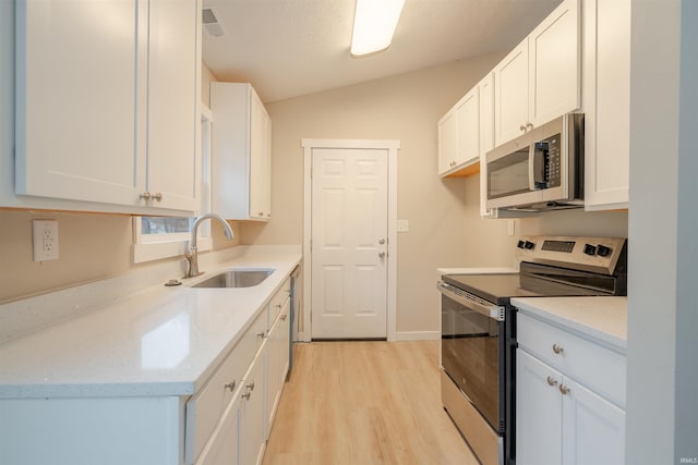 kitchen with vaulted ceiling, white cabinets, and stainless steel appliances