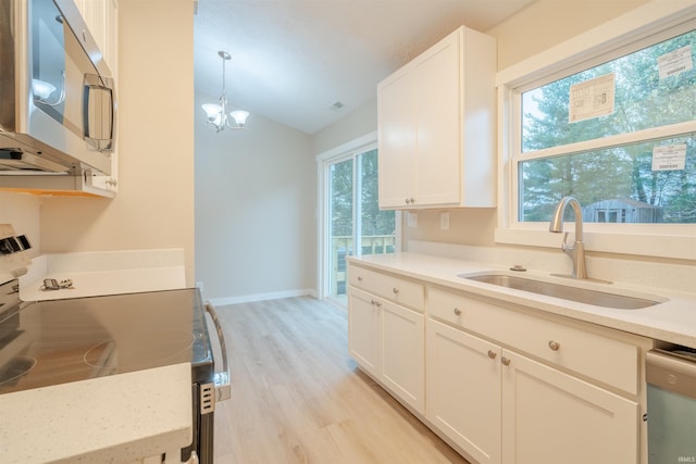 kitchen with white cabinetry, sink, light hardwood / wood-style floors, decorative light fixtures, and appliances with stainless steel finishes