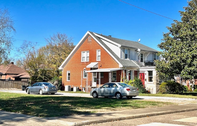 view of front facade featuring central air condition unit, a balcony, and a front lawn