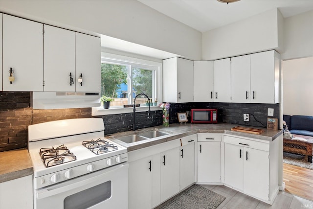 kitchen with light wood-type flooring, backsplash, gas range gas stove, sink, and white cabinets