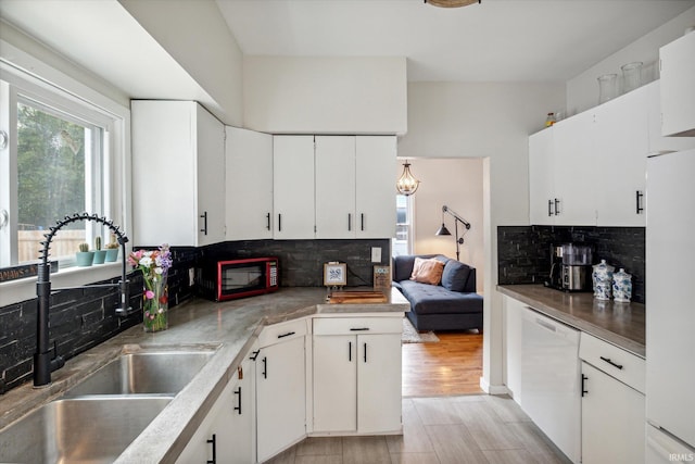 kitchen featuring white appliances, white cabinets, sink, light hardwood / wood-style flooring, and decorative backsplash