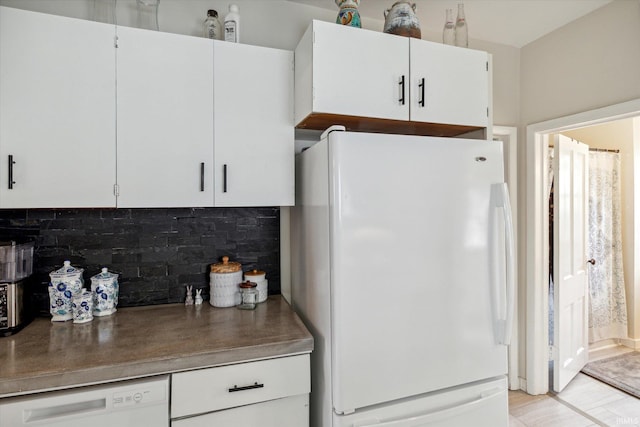 kitchen featuring tasteful backsplash, white cabinets, and white appliances