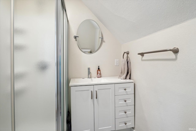 bathroom featuring vanity, an enclosed shower, a textured ceiling, and vaulted ceiling