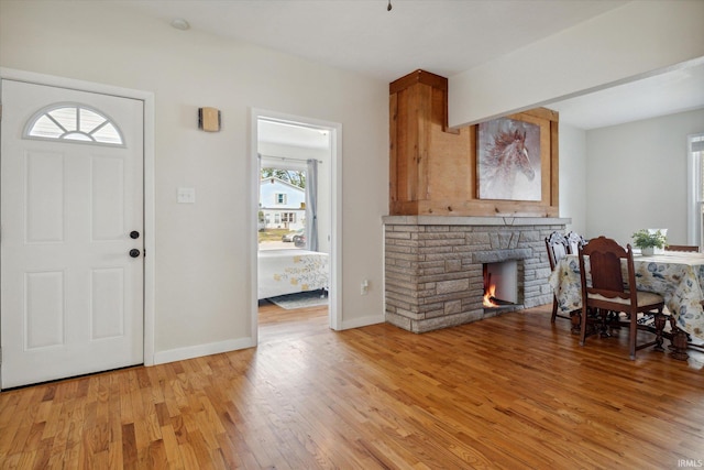 foyer entrance with a fireplace and light hardwood / wood-style flooring