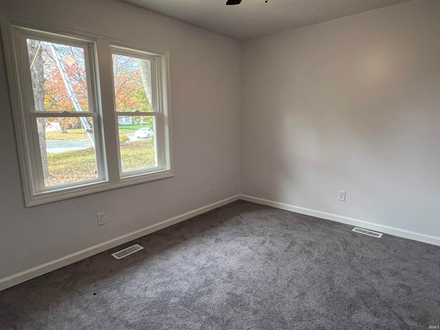 empty room featuring ceiling fan and dark carpet