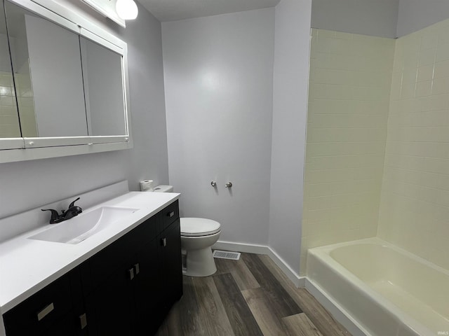 full bathroom featuring washtub / shower combination, hardwood / wood-style floors, vanity, and toilet