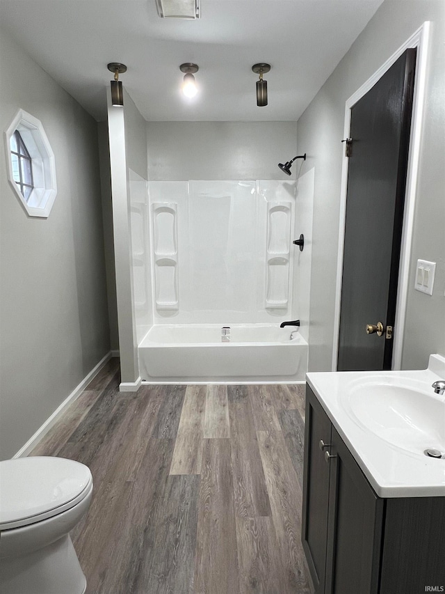 full bathroom featuring washtub / shower combination, vanity, hardwood / wood-style flooring, and toilet