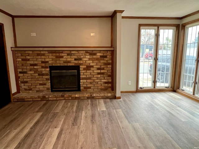 unfurnished living room featuring light hardwood / wood-style floors, crown molding, and a brick fireplace