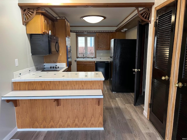 kitchen featuring tile countertops, black appliances, sink, dark hardwood / wood-style floors, and kitchen peninsula