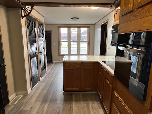 kitchen featuring kitchen peninsula, crown molding, oven, and hardwood / wood-style flooring