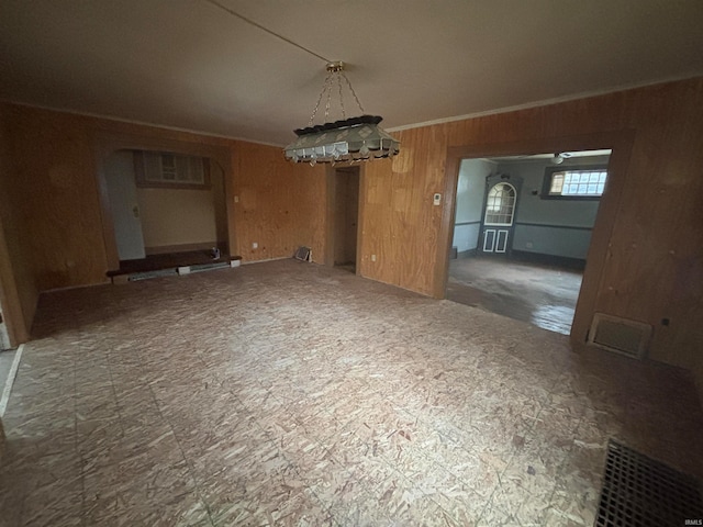 unfurnished dining area with wooden walls and crown molding