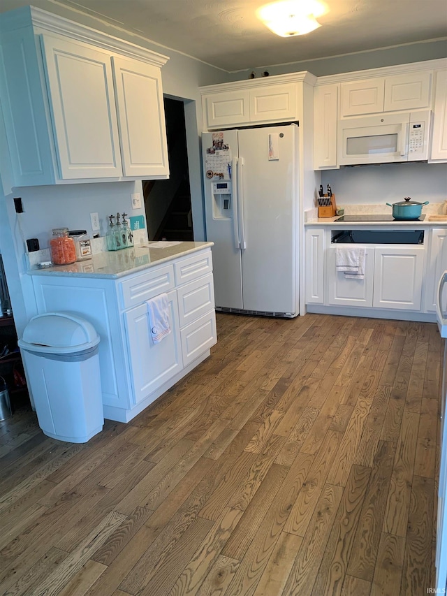 kitchen with dark hardwood / wood-style floors, white cabinetry, light stone counters, and white appliances