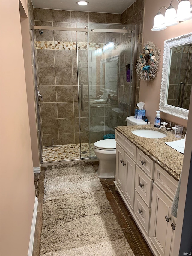 bathroom featuring vanity, an enclosed shower, and toilet