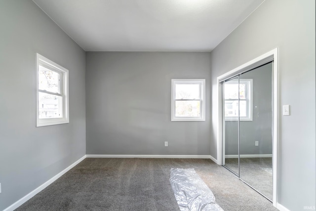 unfurnished bedroom with carpet flooring, a closet, and multiple windows