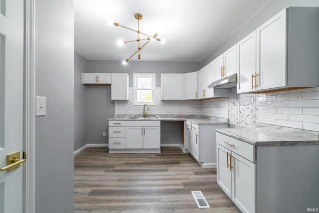 kitchen featuring tasteful backsplash, sink, a chandelier, light hardwood / wood-style floors, and white cabinetry