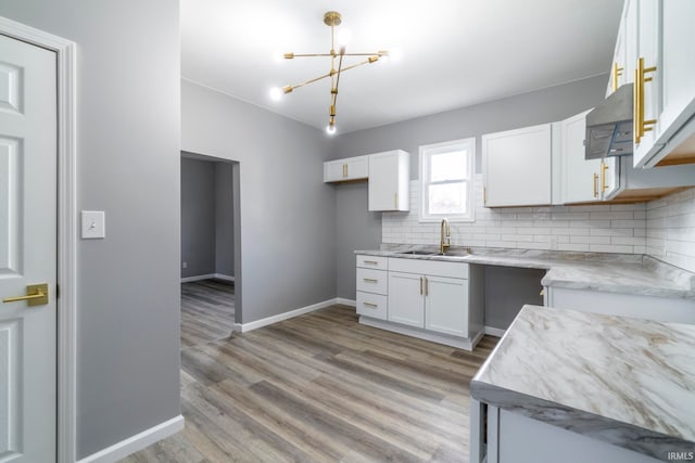 kitchen with sink, light hardwood / wood-style flooring, tasteful backsplash, white cabinetry, and extractor fan