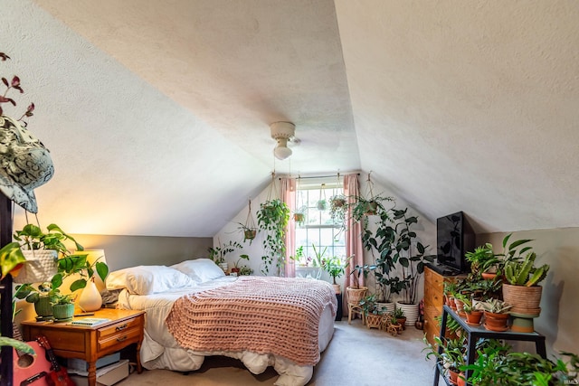 bedroom with vaulted ceiling, ceiling fan, carpet floors, and a textured ceiling