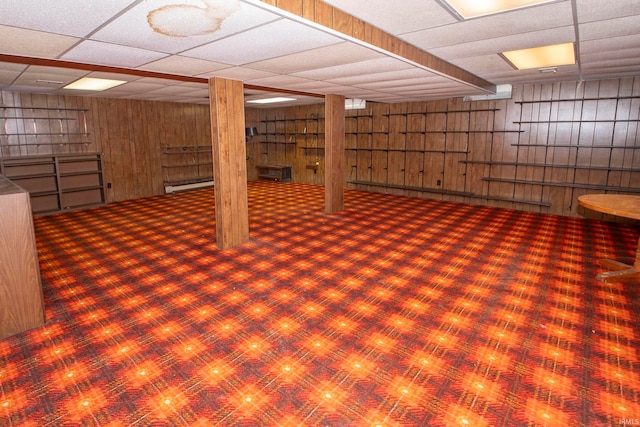 basement with a paneled ceiling and wooden walls